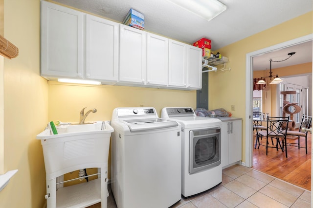 washroom featuring cabinet space, light tile patterned floors, and washer and clothes dryer