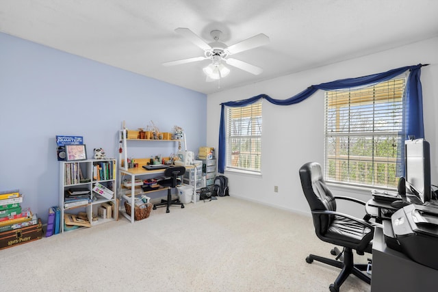 carpeted home office with ceiling fan and baseboards