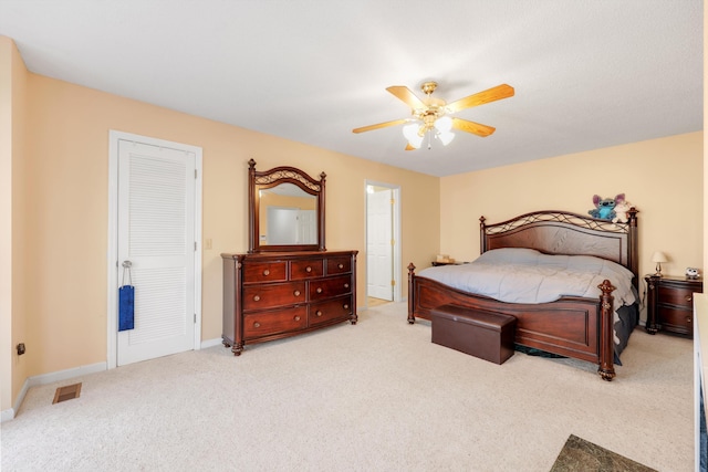 carpeted bedroom with visible vents, baseboards, and a ceiling fan
