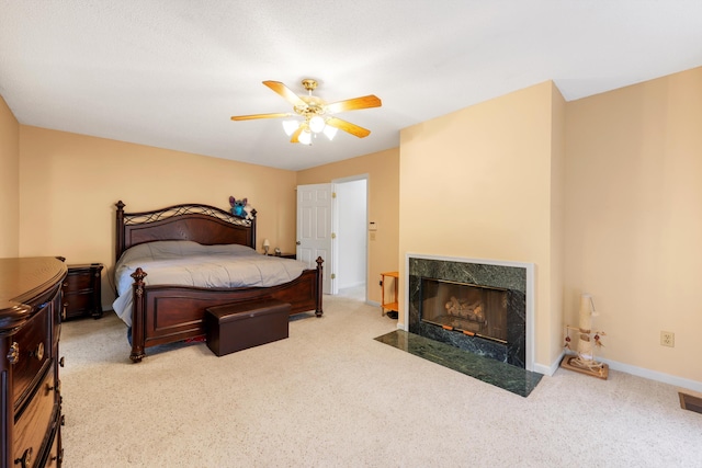 carpeted bedroom featuring baseboards, a ceiling fan, and a fireplace