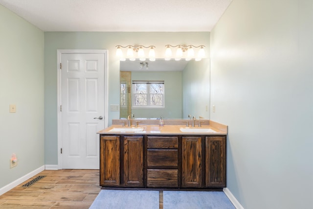 full bathroom featuring a sink, baseboards, double vanity, and wood finished floors