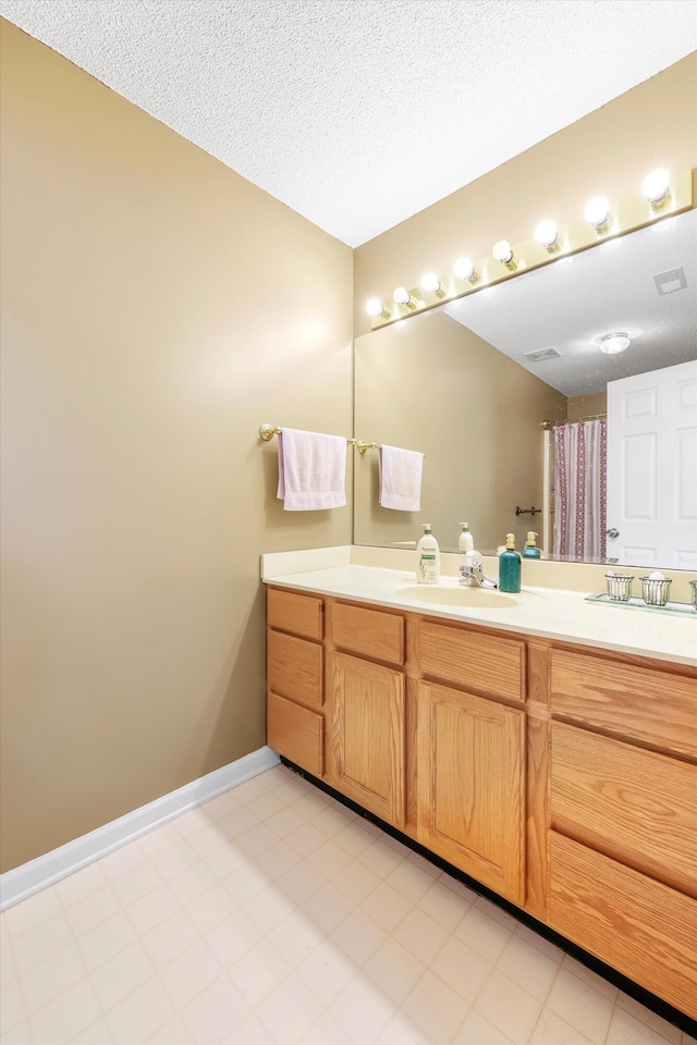 bathroom featuring vanity, a textured ceiling, baseboards, and curtained shower