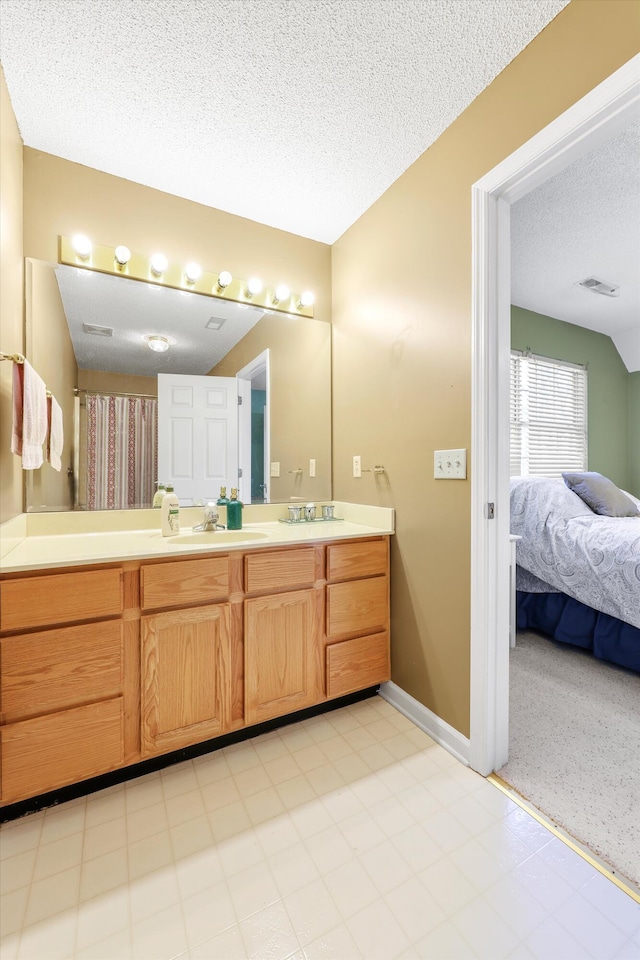 full bathroom featuring baseboards, double vanity, a textured ceiling, visible vents, and a sink