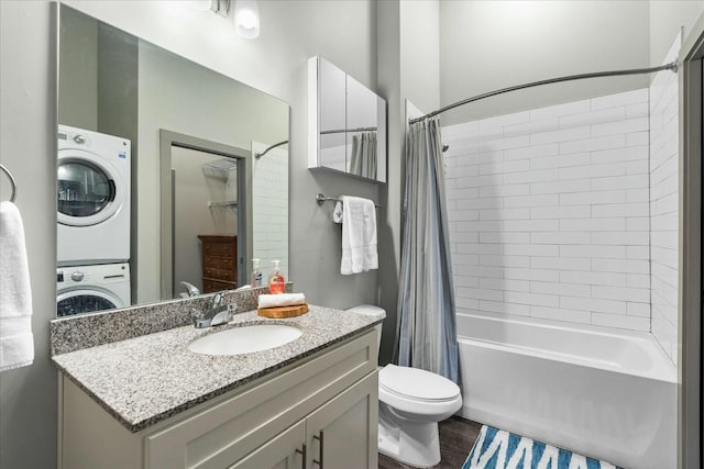 bathroom featuring vanity, stacked washer and dryer, shower / bath combo, toilet, and wood finished floors