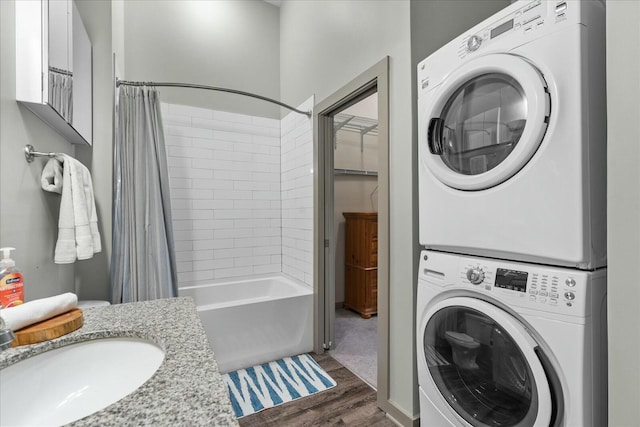 washroom with a sink, stacked washer and clothes dryer, laundry area, and dark wood-type flooring