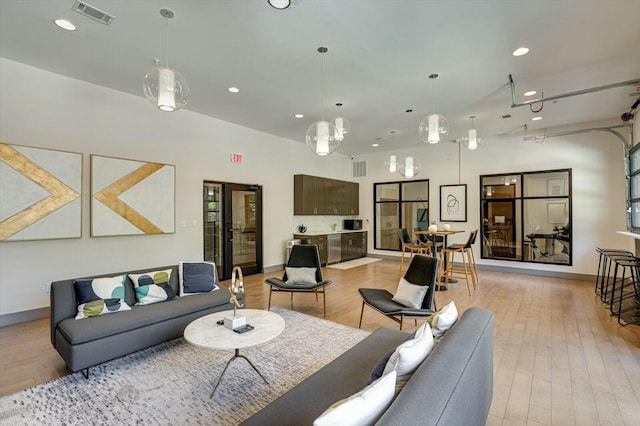 living area with recessed lighting, visible vents, baseboards, and light wood-style flooring