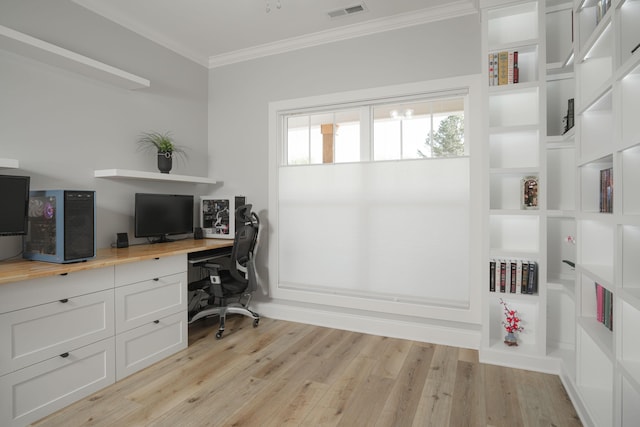 office space with built in desk, crown molding, visible vents, and light wood-style flooring