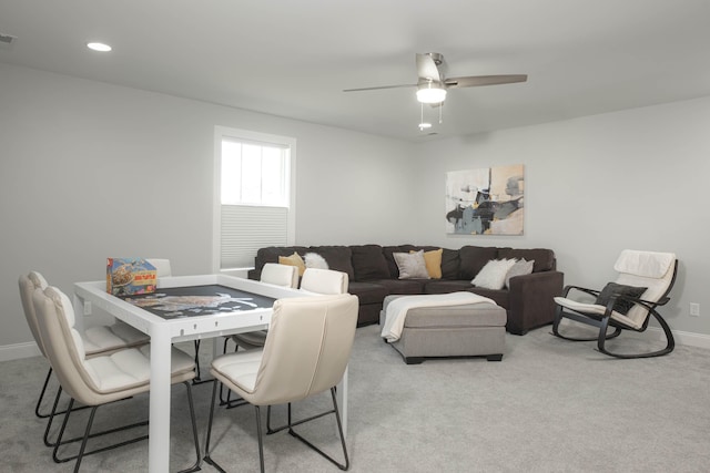 living area with light carpet, baseboards, and a ceiling fan