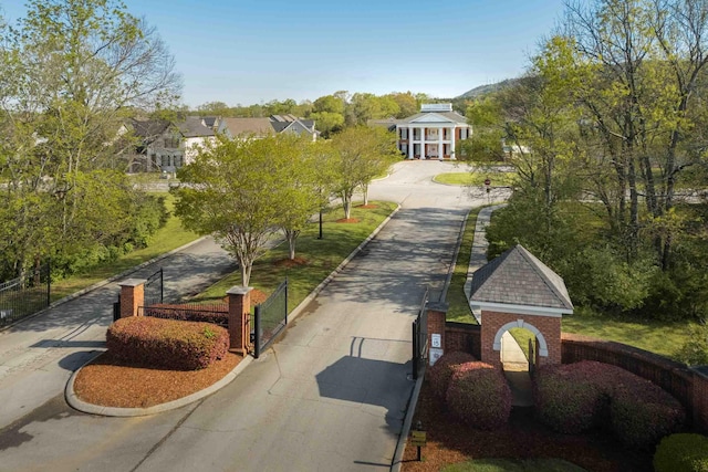 view of property's community with driveway, fence, and a gate