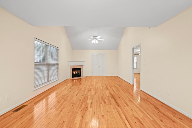 unfurnished living room featuring baseboards, a fireplace, light wood-style floors, ceiling fan, and high vaulted ceiling