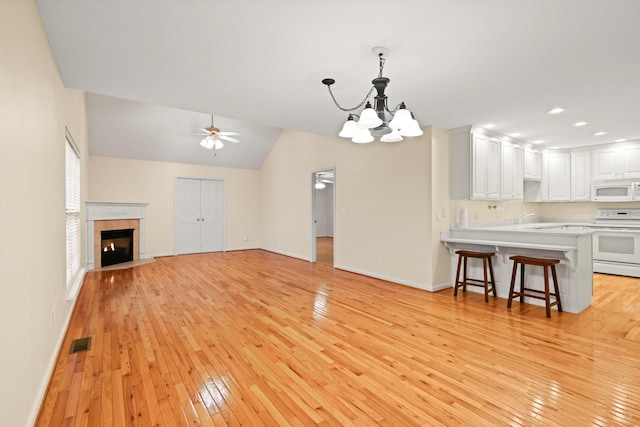 unfurnished living room featuring visible vents, light wood-style flooring, baseboards, and ceiling fan with notable chandelier