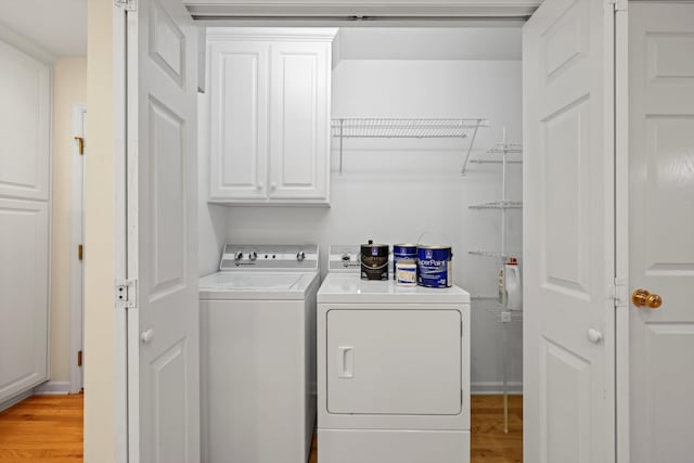 laundry area featuring cabinet space, light wood-style flooring, and washing machine and dryer