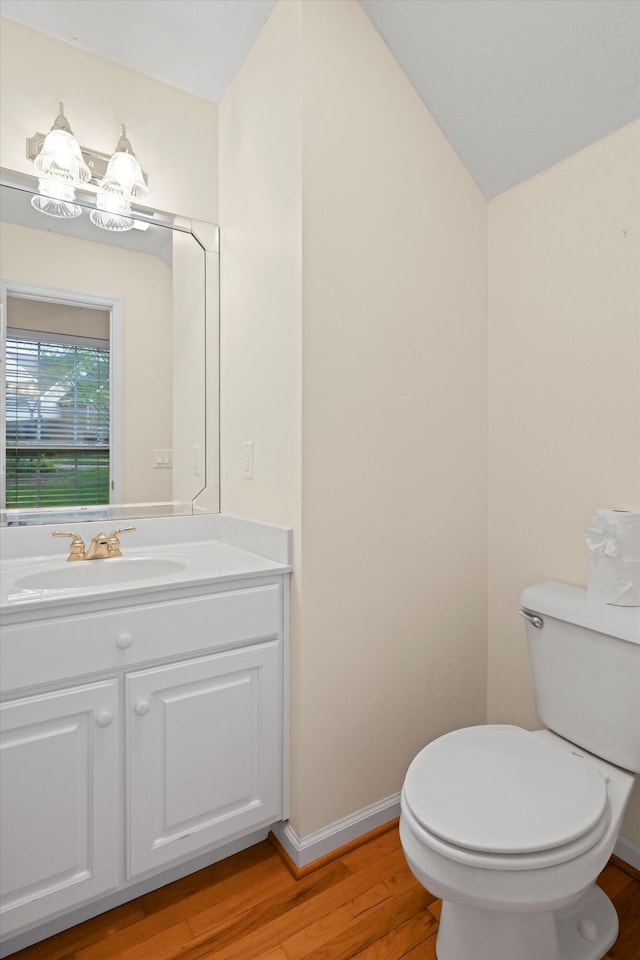 half bath with vanity, an inviting chandelier, toilet, and wood finished floors