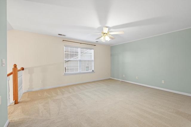 carpeted spare room with visible vents, baseboards, and a ceiling fan