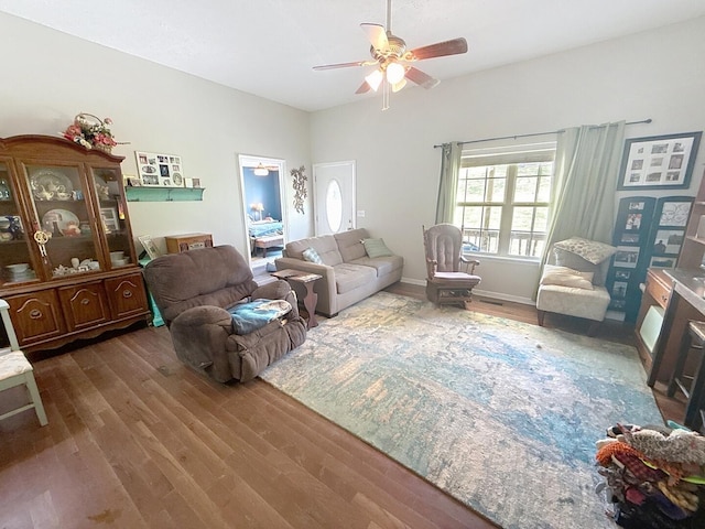 living room with baseboards, wood finished floors, and ceiling fan