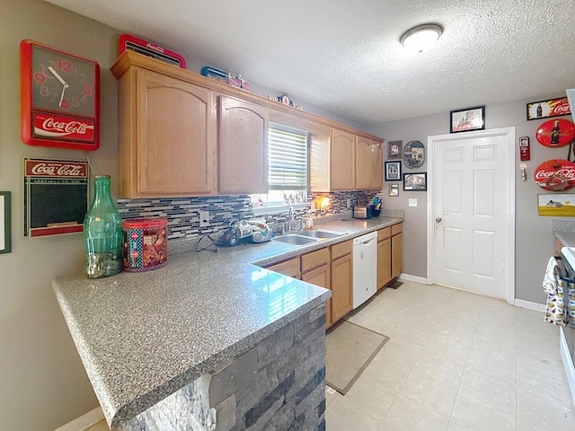 kitchen featuring baseboards, a textured ceiling, backsplash, white dishwasher, and a sink