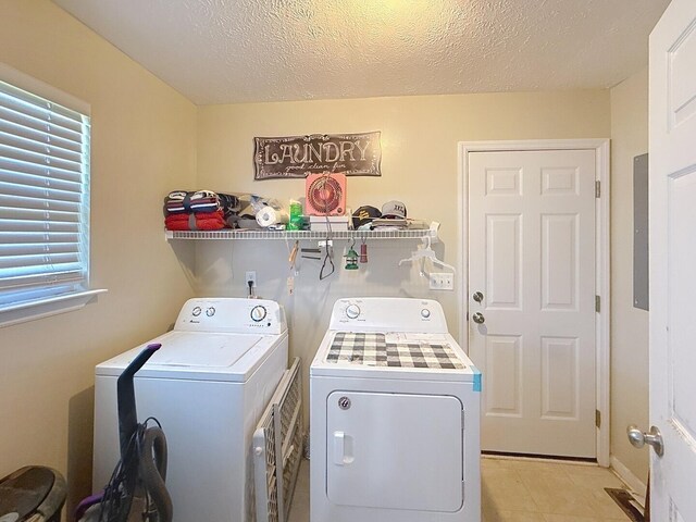 clothes washing area featuring light tile patterned floors, washing machine and dryer, laundry area, and a textured ceiling