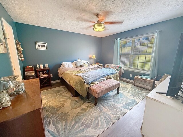 bedroom with baseboards, a ceiling fan, and a textured ceiling
