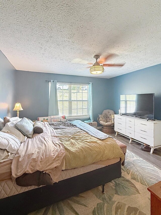 bedroom with ceiling fan, a textured ceiling, and wood finished floors