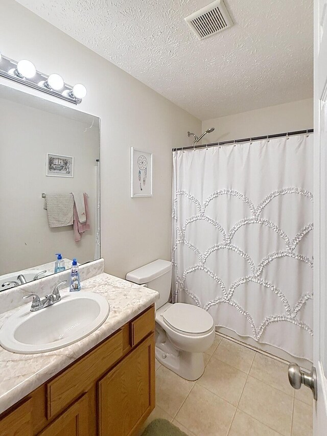 bathroom with visible vents, toilet, a textured ceiling, vanity, and tile patterned floors