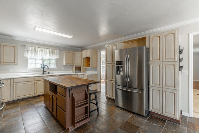 kitchen featuring butcher block countertops, ornamental molding, stainless steel refrigerator with ice dispenser, a sink, and light brown cabinetry