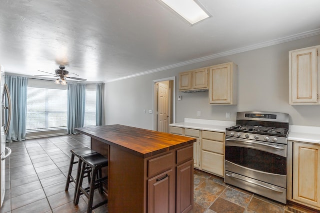 kitchen featuring a kitchen bar, light brown cabinetry, ornamental molding, gas stove, and wooden counters