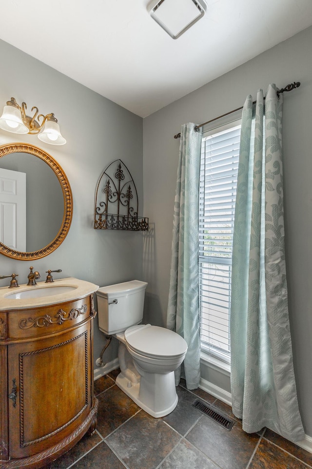 bathroom featuring visible vents, baseboards, toilet, stone finish floor, and vanity