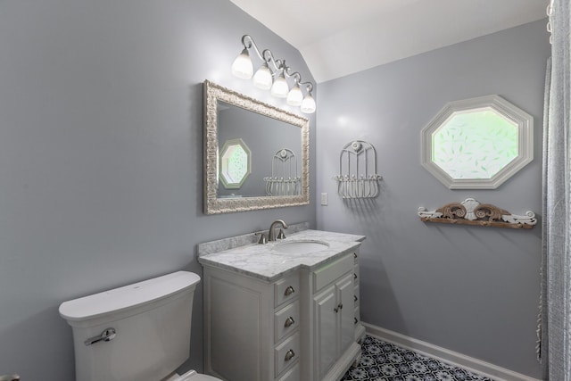 bathroom featuring toilet, vanity, baseboards, and lofted ceiling