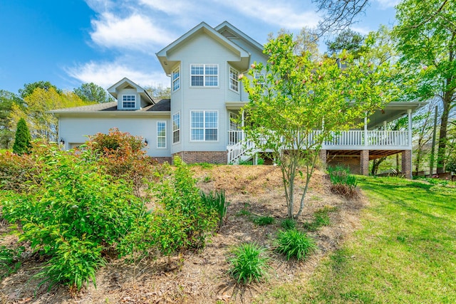 rear view of property featuring a yard and stairs