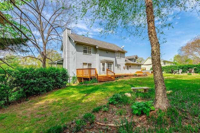 rear view of property featuring a chimney, a wooden deck, and a lawn