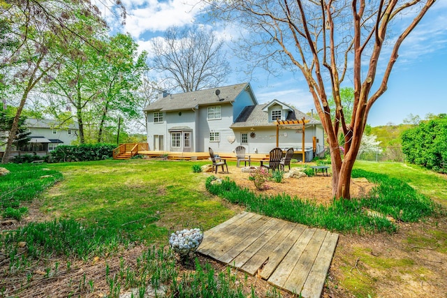 rear view of house with a fire pit, a deck, fence, and a lawn