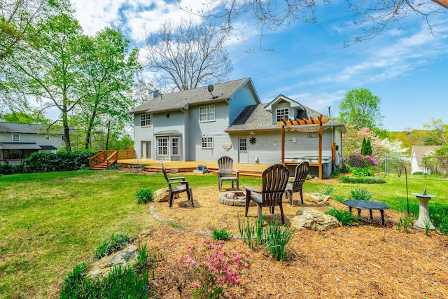 rear view of house with a pergola, a fire pit, a deck, fence, and a lawn