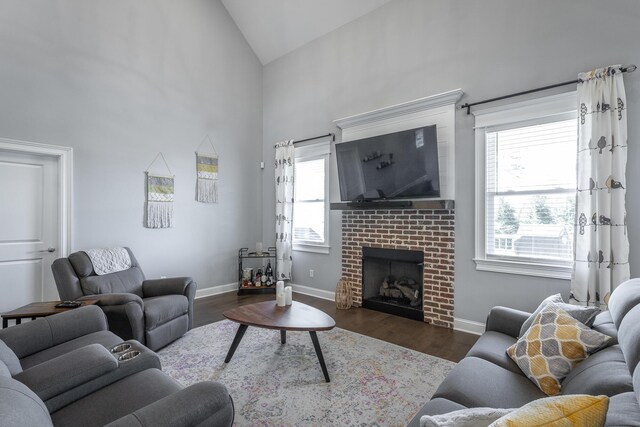 living area with baseboards, wood finished floors, a fireplace, and high vaulted ceiling
