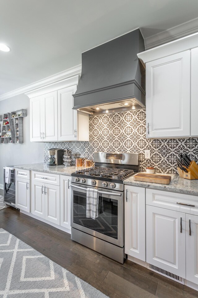 kitchen featuring white cabinets, backsplash, ornamental molding, premium range hood, and gas range
