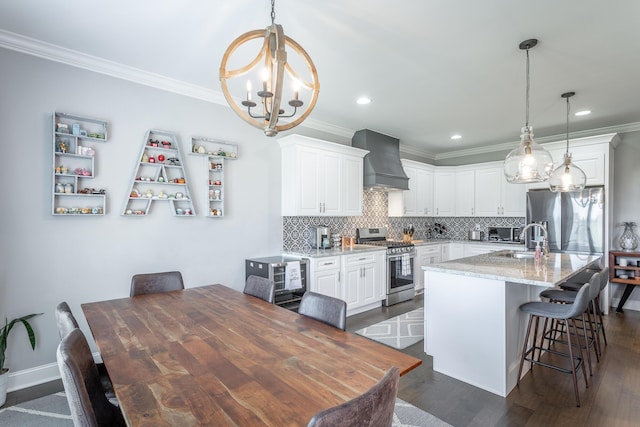 kitchen with premium range hood, crown molding, appliances with stainless steel finishes, and a notable chandelier