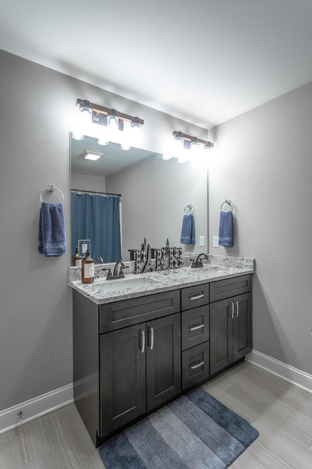 bathroom with baseboards, a sink, and double vanity