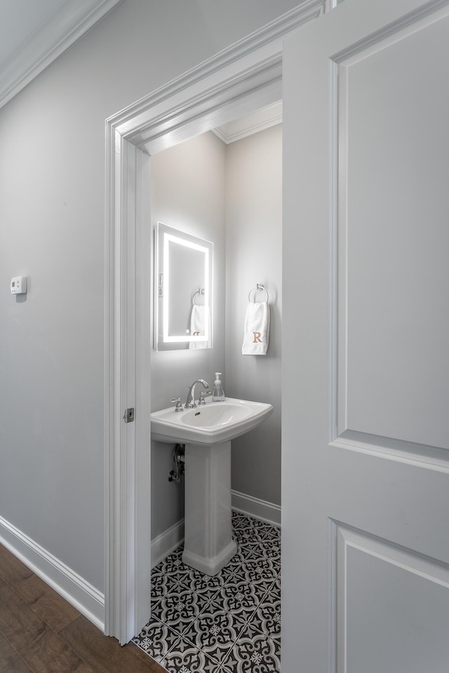 bathroom featuring baseboards, crown molding, and a sink