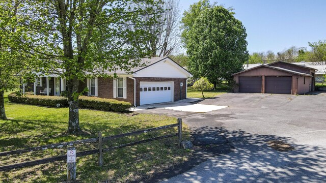 ranch-style home with brick siding, a detached garage, a front lawn, and fence