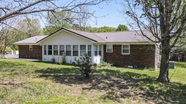 rear view of property with brick siding, a yard, central air condition unit, and metal roof