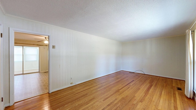 unfurnished room with visible vents, ornamental molding, baseboards, light wood-style flooring, and a textured ceiling