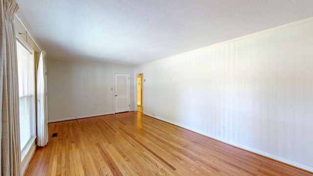 empty room featuring a healthy amount of sunlight, a textured ceiling, and light wood-style flooring