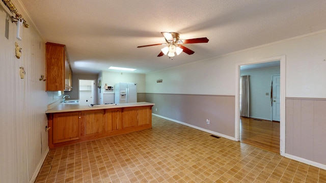 kitchen featuring light floors, light countertops, a peninsula, white fridge with ice dispenser, and ceiling fan