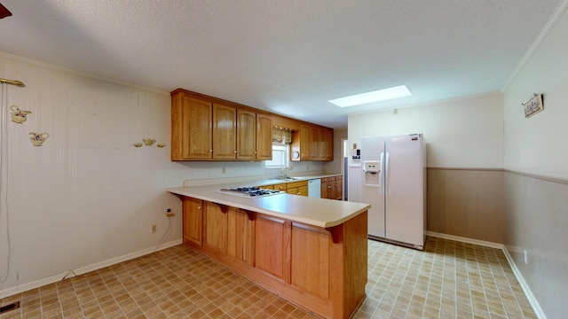 kitchen with a sink, a skylight, white appliances, light countertops, and a peninsula