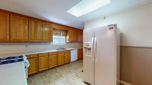 kitchen with light floors, brown cabinets, a sink, and white appliances