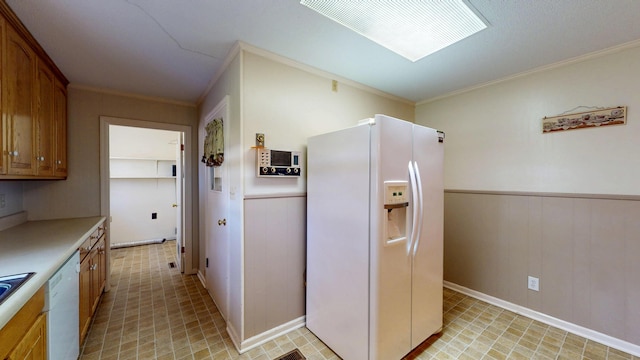 kitchen with light countertops, crown molding, wainscoting, and white appliances