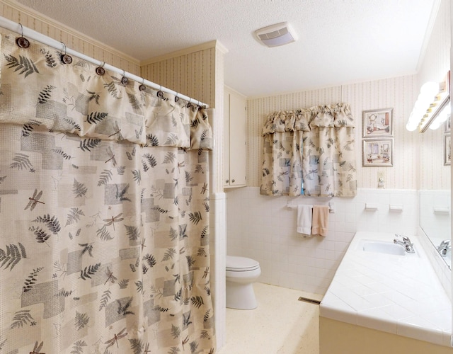 bathroom with toilet, crown molding, a wainscoted wall, and wallpapered walls