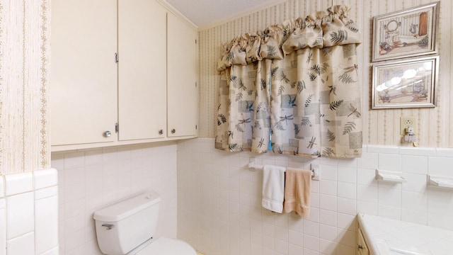 bathroom with toilet, tile walls, wainscoting, wallpapered walls, and crown molding