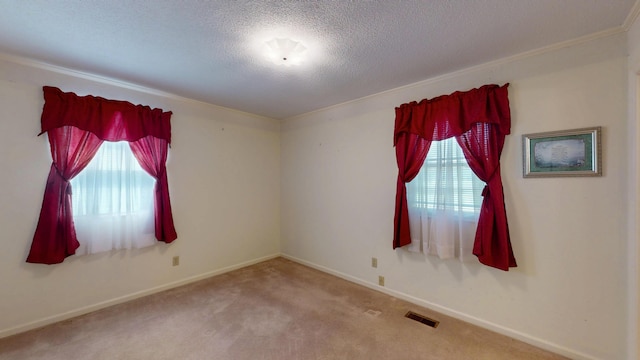 carpeted empty room with baseboards, a textured ceiling, and visible vents