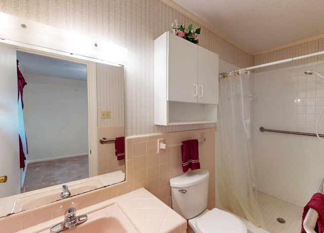 bathroom with wallpapered walls, a shower stall, toilet, tile walls, and wainscoting