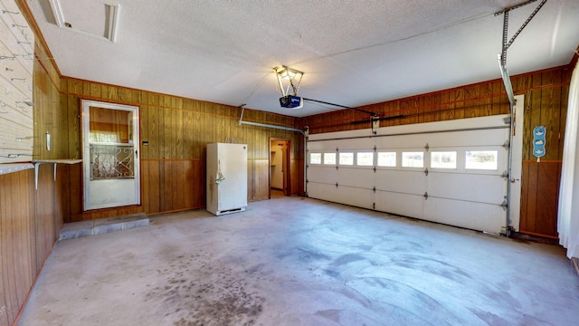 garage featuring freestanding refrigerator, wood walls, and a garage door opener